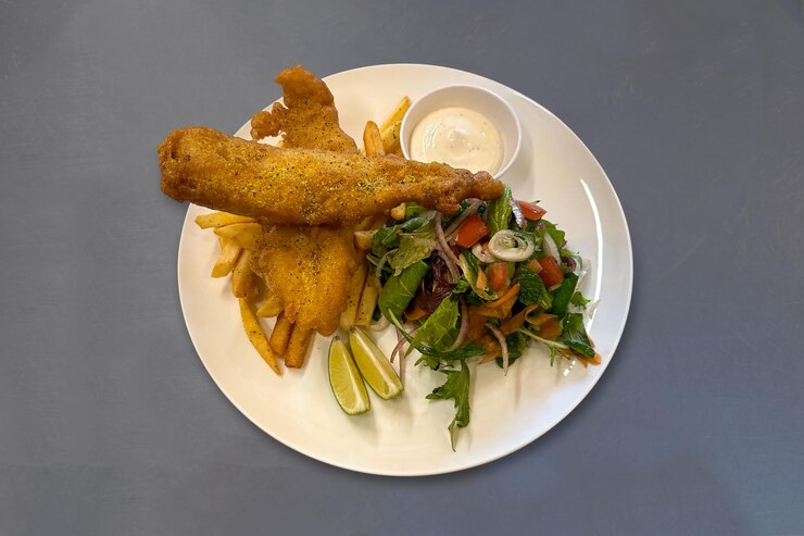 Steak de pescado frito con ensalada patatas fritas y salsa de mayonesa Fillet de Pangasius frito