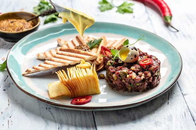 Steak Tartar mit Brottoast auf Teller serviert. Leckeres Frühstück oder Snack. Französische Küche Mahlzeit aus rohem Fleisch