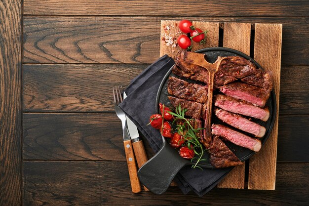 Steaks Tbone Geschnittenes Rindfleisch gegrilltes Tbone oder Porterhouse-Fleischsteak mit Gewürzen Rosmarin und Pfeffer auf schwarzem Marmorbrett auf altem Holzhintergrund Draufsicht Mock up