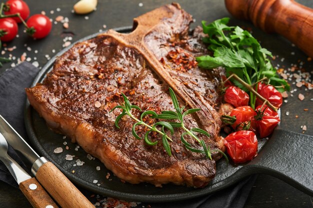 Steaks Tbone Geschnittenes Rindfleisch gegrilltes Tbone oder Porterhouse-Fleischsteak mit Gewürzen Rosmarin und Pfeffer auf schwarzem Marmorbrett auf altem Holzhintergrund Draufsicht Mock up