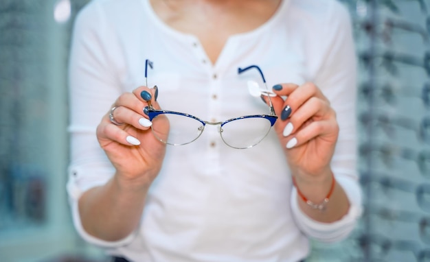 Stehen Sie mit Brille im Optikgeschäft Eine Frauenhand wählt eine Brille aus
