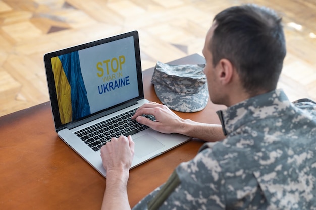 Stehen Sie mit der Ukraine auf Social Media-Konzepthintergrund mit Laptop. Militär mit der Flagge der Ukraine