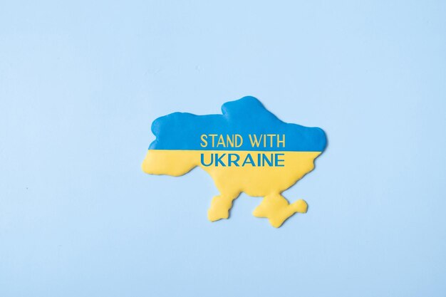 Stehen Sie mit Ukraine-Text auf der Karte Ukraine in den gelbblauen Farben der Nationalflagge auf einer Draufsicht des blauen Hintergrundes