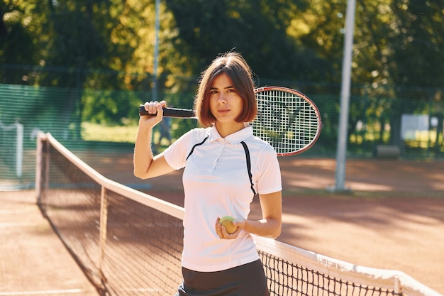 Stehend mit Schläger in der Hand Tennisspielerin ist tagsüber auf dem Platz