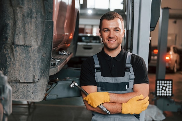 Stehend mit verschränkten Armen Mann in Uniform arbeitet im Autoservice