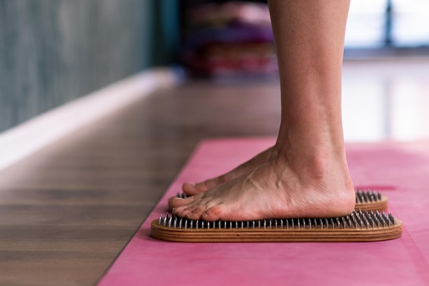 Foto stehende barfüßige frau macht nagelreflexzonenmassage in einem professionellen yoga-kurs