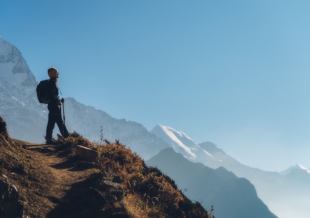 Stehende junge Frau mit Rucksack auf dem Hügel und Blick auf Berge