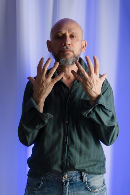 Stehender Mann macht Handgesten Studio-Porträt mit blauem Filter, weißem Vorhanghintergrund