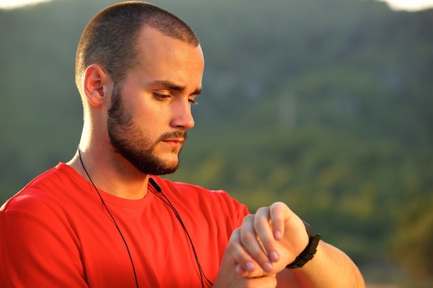 Stehendes äußeres Überprüfen des athletischen Mannes Uhr