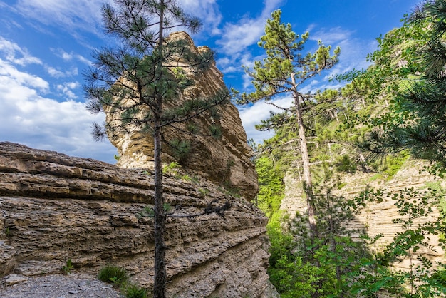 Steile Klippen aus geschichteten Felsen in Nahaufnahme auf klaren Tageswolken am Himmel x A