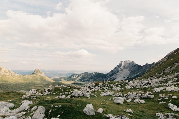 Steinblöcke liegen auf einem grünen Rasen vor dem Hintergrund der Berge