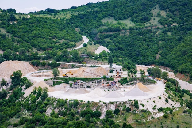 Steinbruch für die Gewinnung von Mineralien mit Ausrüstung und Maschinen und Straße in den mit Wäldern bedeckten Rhodopen