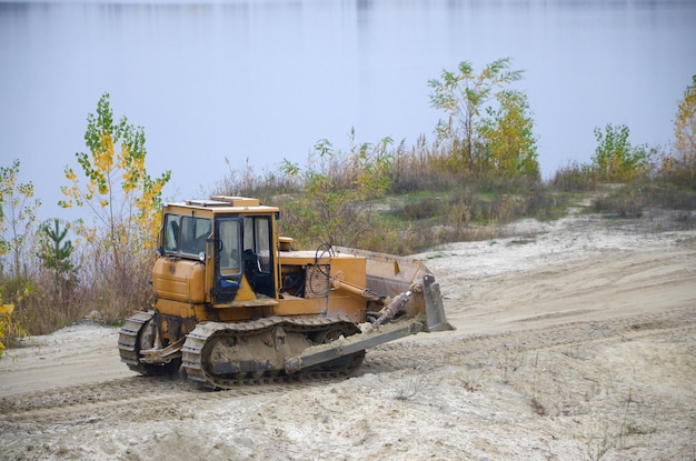 Steinbruchaggregat mit Schwerlastmaschinen Caterpillar-Lader Bagger mit Baggerlader, der zum Steinbruch der Baustelle fährt