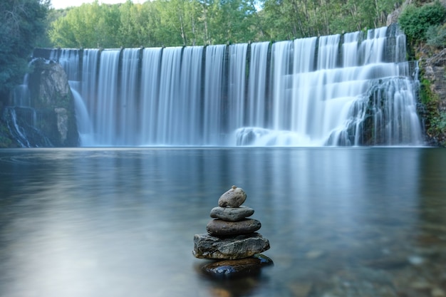 Steine im Fluss- und Wasserfallhintergrund