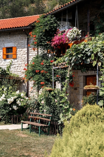 Steinhaus mit Ziegeldach, umgeben von viel Grün im Garten. Sommer Hintergrund