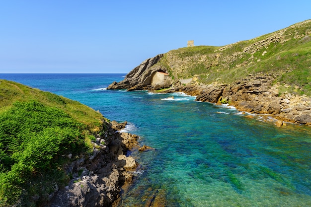 Steinhaus versteckt zwischen den Felsen auf einer Klippe vom Meer, Santander, Spanien