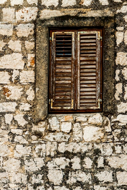 Steinmauer und Fenster mit geschlossenen Fensterläden aus Holz