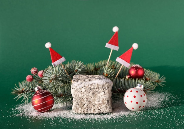 Steinpodest mit Winterweihnachtsferiendekor rot-weiße Kugeln Weihnachtsmannmützen Beeren auf Tannenzweigen