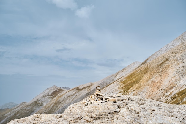 Steinpyramide auf einem Pass im Hochgebirge vor dem Hintergrund des Himmels und des Pirin-Gebirges