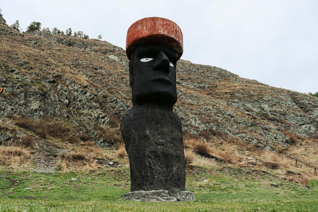 Steinstatue in einem roten Hut ist im Boden begraben