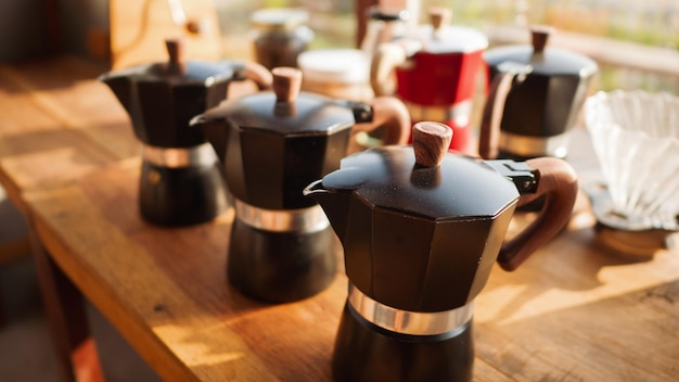 Stellen Sie die alte Kaffeemaschine der Mokkakanne auf den Holztisch und die Kaffeetasse im Café-Shop