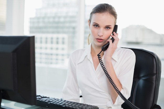 Stern, mulher de negócios, sentada, escrivaninha, telefone, olhar, câmera