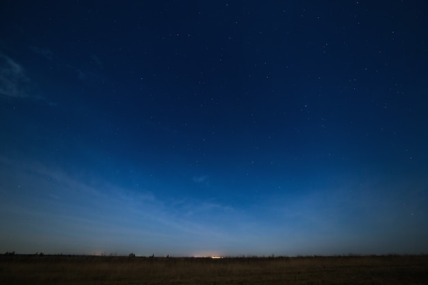 Sterne am Nachthimmel mit Lichtern der Stadt am Horizont. Die Landschaft wird bei Mondschein fotografiert.