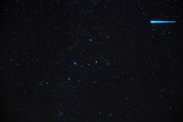 Sternschnuppe Meteoritenkomet auf dem Hintergrund eines blauen dunklen Sternenhimmels mit Galaxien und Nebeln