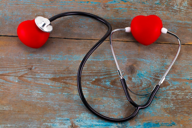 Stethoskop mit rotem Herzen auf Holzhintergrund.