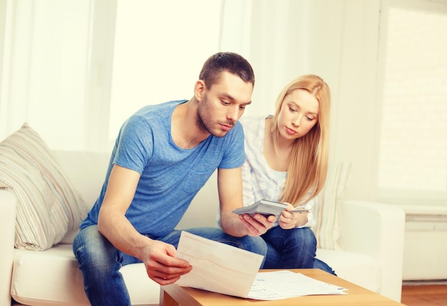 Steuer-, finanz-, familien-, haus- und glückskonzept - beschäftigtes paar mit papieren und taschenrechner zu hause