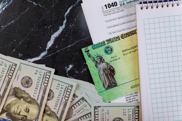 Steuererklärung und Erstattungsscheck US-Steuerformular, Dollar-Bargeld und leeres Notizbuch 1040 individuelles Steuerformular