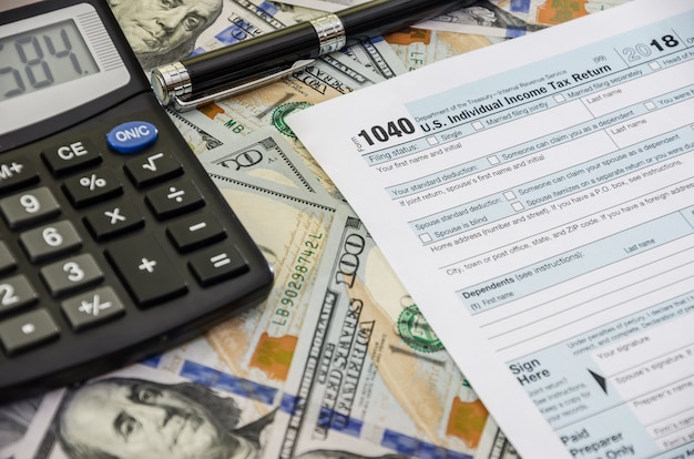 Steuerformulare 1040 mit Stift und Taschenrechner auf Geldhintergrund