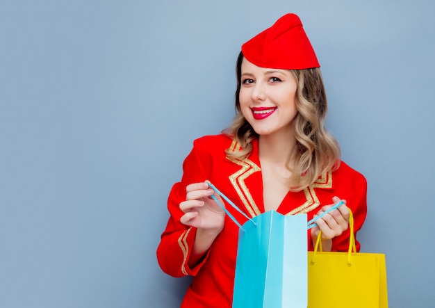 Stewardess in roter Uniform mit Einkaufstüten.