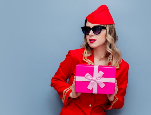 Stewardess in roter Uniform mit Weihnachtsgeschenk Bord