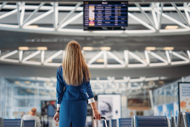 Stewardess schaut auf Anzeigetafel im Flughafen