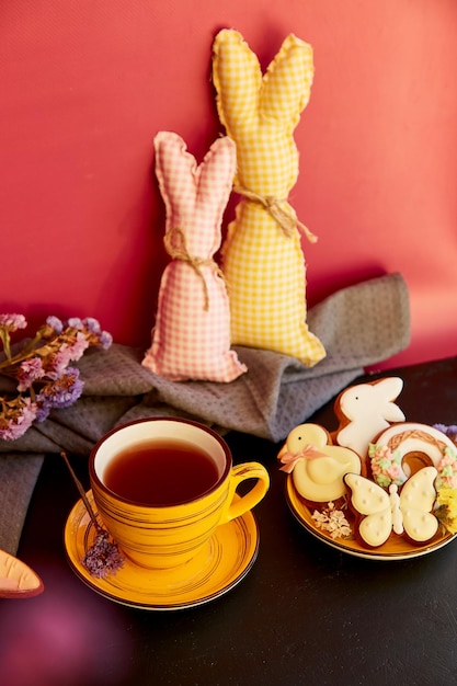 Ästhetische gelbe Teetasse und Osterplätzchen mit Dekorationen, die Hasenspielzeug basteln Feiertagsessen-Teezeit