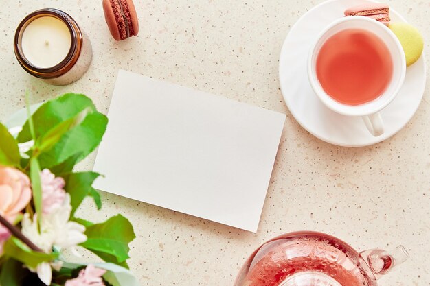 Ästhetische Teezeit und festliche Mock-up-Briefpapierkarte Ort zum Wünschen oder Text Tasse Tee mit Makronen und natürlichem Tee in Glasteekanne Gemütliches Zuhause mit Kerzendessert Kopierbereich