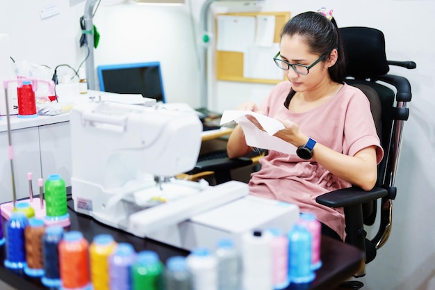 Stickerei Handwerk Hobbys KMU-Unternehmen Familienunternehmen Porträt asiatischer Designerinnen, die Muster mit automatischen Stickmaschinen im Kundenauftrag entwerfen