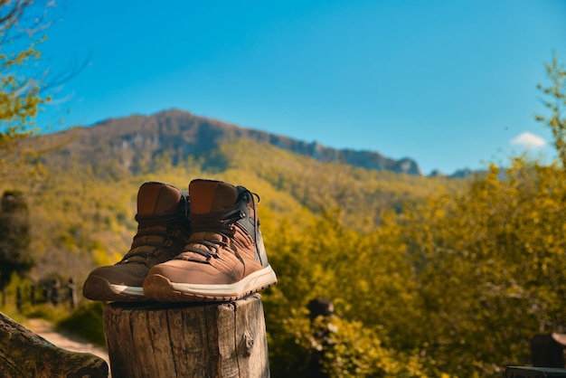 Stiefel eines Wanderers, der sich nach einem Ausflug an einen Pfahl mit einem Berg im Hintergrund lehnt