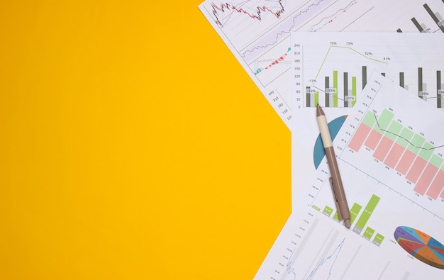 Stift mit Grafiken und Diagrammen auf gelbem Grund. Geschäftsplan, Finanzanalyse, Statistik. Draufsicht. Speicherplatz kopieren