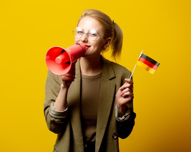 Stil blonde Frau in Jacke mit deutscher Flagge und Megaphon auf gelb