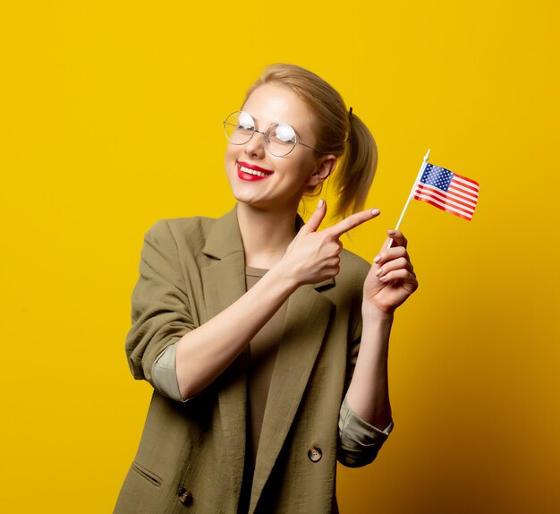 Stil blonde Frau in Jacke mit Flagge der USA auf gelb