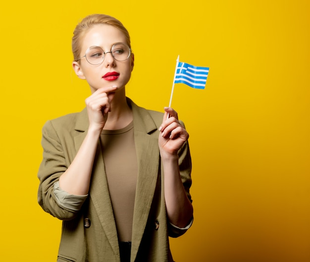 Stil blonde Frau in Jacke mit griechischer Flagge auf gelb