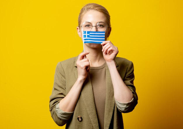 Stil blonde Frau in Jacke mit griechischer Flagge auf gelb