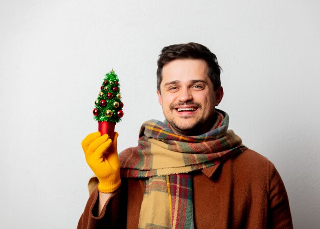 Stil Mann in Mantel und Schal mit Weihnachtsbaum