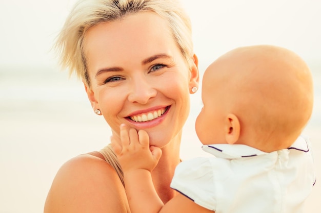 Stillen auf Stillkonzept Schöne Frau mit Baby am Sommerstrand bei Sonnenuntergang