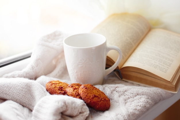 Stillleben Becher altes Buch und Kekse auf der Fensterbank liegen