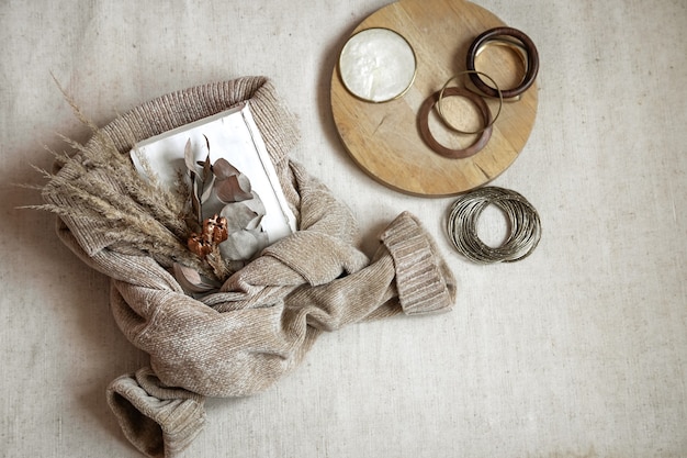 Stillleben der Details. Bouquet von getrockneten Blumen auf einem warmen Pullover und Frauenarmbänder Draufsicht, Herbstkonzept.