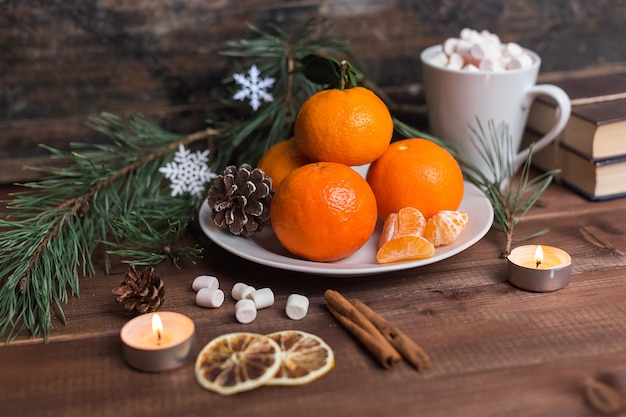 Stillleben des neuen Jahres mit frischen Mandarinen auf einer Platte mit Eibisch und Zimt