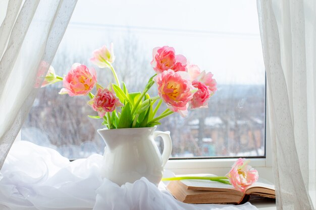 Stillleben eine Vase mit Tulpen und einem alten Buch am Fenster